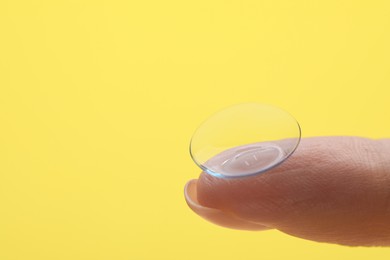 Photo of Woman with contact lens on yellow background, closeup. Space for text