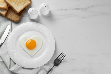 Romantic breakfast with heart shaped fried egg served on white marble table, flat lay. Space for text