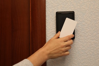 Woman opening magnetic door lock with key card indoors, closeup