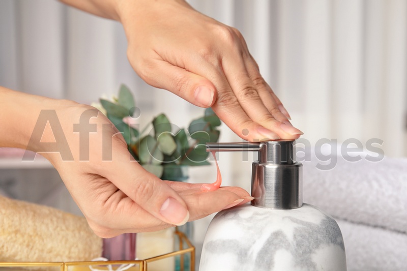 Woman using soap dispenser indoors, closeup view