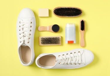 Flat lay composition with stylish footwear and shoe care accessories on yellow background