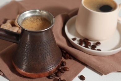 Photo of Turkish coffee. Cezve and cup with hot aromatic coffee on table