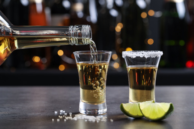 Pouring Mexican Tequila from bottle into shot glass on bar counter