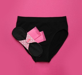 Women's underwear with disposable and reusable menstrual pads on pink background, top view