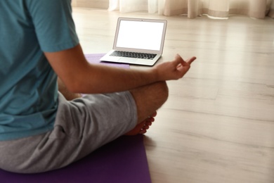 Man practicing yoga while watching online class at home during coronavirus pandemic, closeup. Social distancing