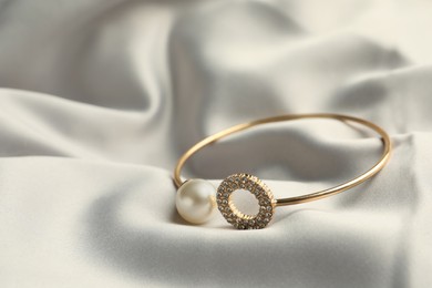 Elegant bracelet with pearl on grey silk, closeup