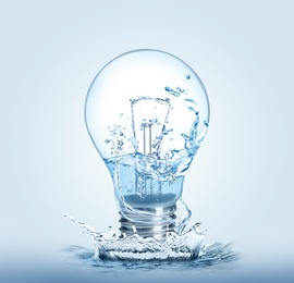 Light bulb with water splashes on light background. Alternative energy source