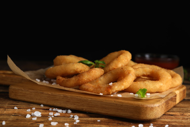 Delicious onion rings on wooden table, closeup