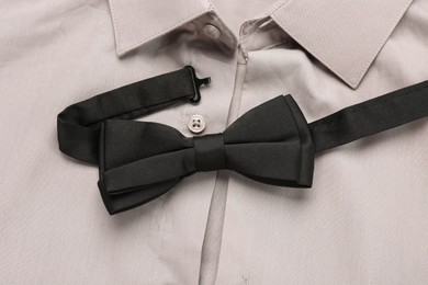 Stylish black bow tie on beige shirt, closeup