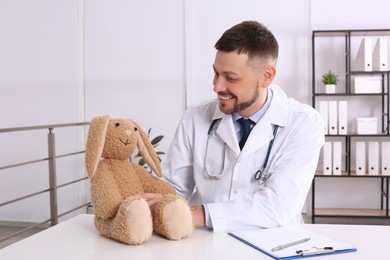 Pediatrician with toy bunny at desk in office