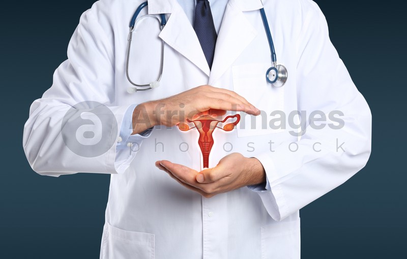 Doctor demonstrating virtual icon with illustration of female reproductive system on dark background, closeup. Gynecological care 