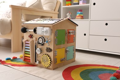 Busy board house on floor indoors. Baby sensory toy