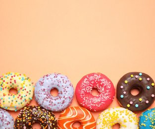 Delicious glazed donuts on orange background, flat lay. Space for text