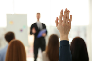 Young woman raising hand to ask question at business training indoors, closeup
