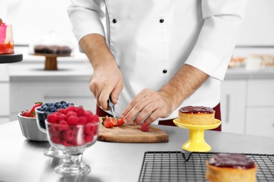 Photo of Male pastry chef preparing dessert at table in kitchen, closeup