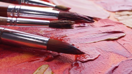 Photo of Many brushes on artist's palette with mixed paints, closeup