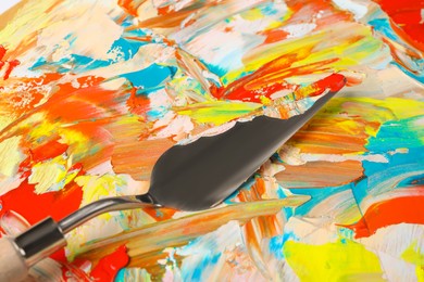 Closeup view of dirty artist's palette with painting knife as background