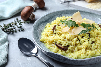 Photo of Delicious risotto with cheese and mushrooms on grey marble table, closeup