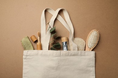 Photo of Bag with eco friendly products on craft paper, flat lay