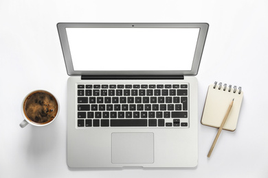 Photo of Modern laptop, stationery and cup of coffee on white background, top view