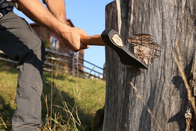 Man with axe cutting wood outdoors, closeup
