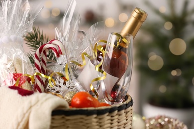 Wicker basket with Christmas gift set on blurred background, closeup