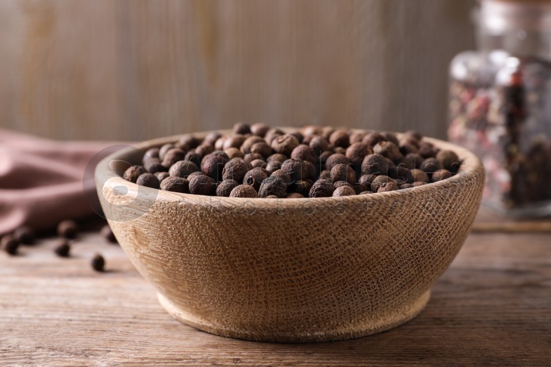 Peppercorns in bowl on wooden table, closeup