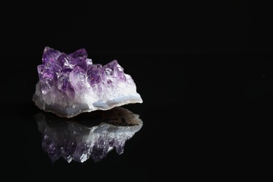 Photo of Beautiful purple amethyst gemstone on black background. Space for text
