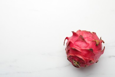Photo of Delicious red pitahaya fruit on white marble table, top view. Space for text