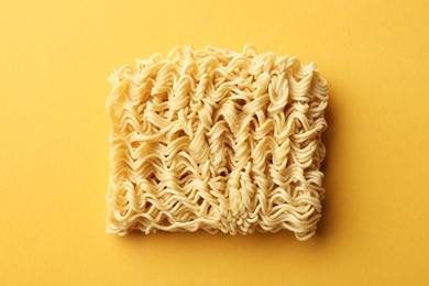 Block of quick cooking noodles on color background, top view