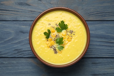 Delicious creamy corn soup on blue wooden table, top view