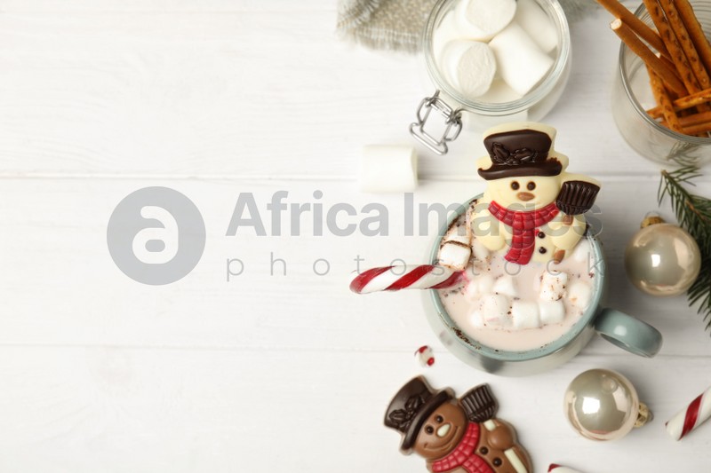 Flat lay composition with funny chocolate snowmen candies on white wooden table. Space for text
