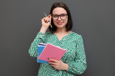 Photo of Happy young intern with notebooks and pen on grey background