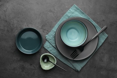 Stylish empty dishware and cutlery on grey table, flat lay