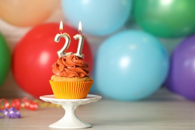 21th birthday, coming of age party. Delicious cupcake with number shaped candles on wooden table, space for text