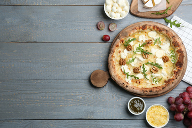 Photo of Delicious cheese pizza with walnuts served on grey wooden table, flat lay. Space for text