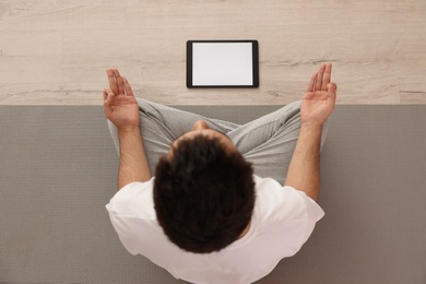 Man practicing yoga while watching online class at home during coronavirus pandemic, top view. Social distancing