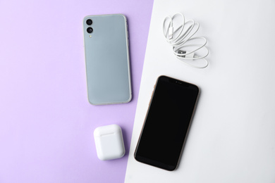 USB charge cable, wireless earphone case and smartphones on color background, flat lay. Modern technology