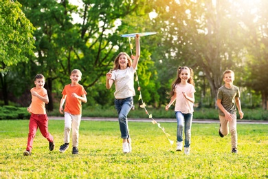 Image of School holidays. Group of happy children playing with kite outdoors 