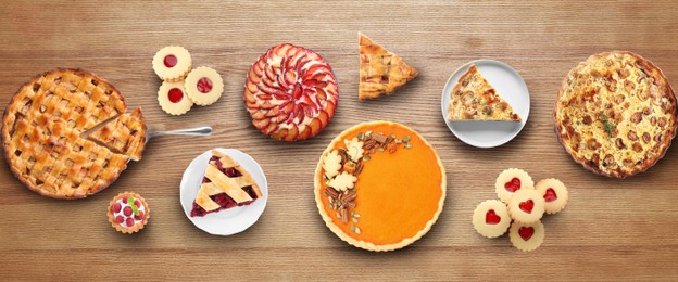 Flat lay composition with different delicious pies on wooden table. Banner design