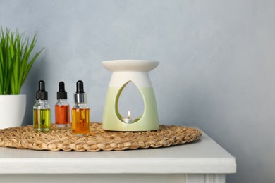 Aroma lamp and essential oils on white table