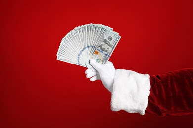Santa holding dollar bills on red background, closeup