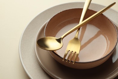 Stylish empty dishware and cutlery on beige background, closeup
