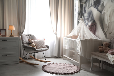 Baby room interior with stylish crib and floral wallpaper