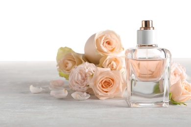 Elegant bottle of perfume and flowers on light background, space for text