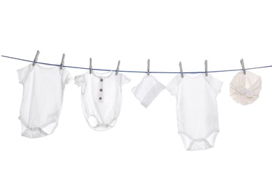 Different baby clothes drying on laundry line against white background