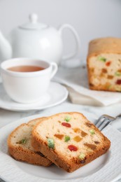 Delicious cake with candied fruits and tea on table, closeup