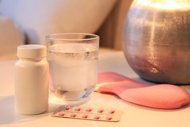 Sleeping mask, pills and glass of water on nightstand indoors. Insomnia treatment