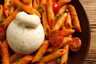 Delicious pasta with burrata cheese and tomatoes on table, top view