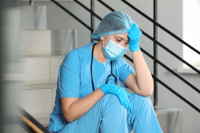Exhausted doctor sitting on stairs in hospital